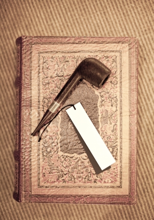 white tag on Tobacco Pipe and old leather covered book, shallow focusの写真素材