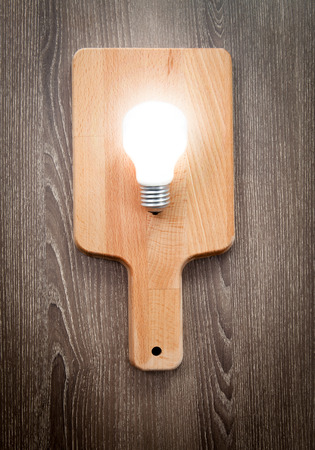 Light bulb on chopping board, serve idea concept, wood tableの写真素材