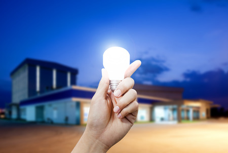 Light energy for industry, Hand holding light bulb in industrial topicの写真素材