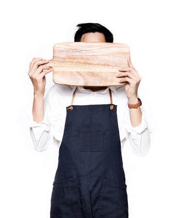 A portrait of chef holding the hardboard of his faceの写真素材