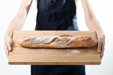Hand holding a French baquette bread on wood plateの写真素材