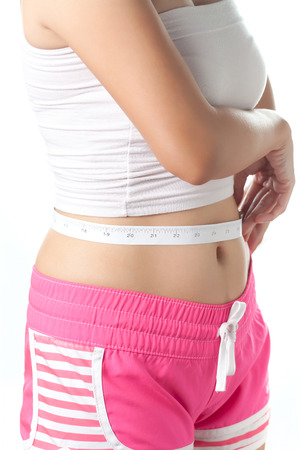 Young woman measuring her waistline with measuring tape Beauty body care and dietの写真素材