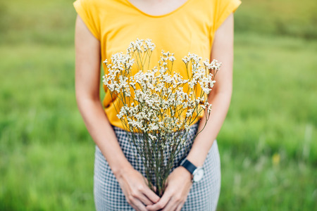 Woman hands holding a flower in green meadow with focus on a flowerの写真素材