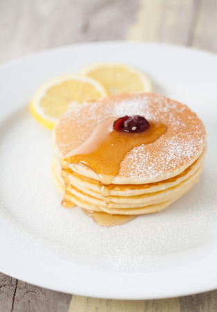 Stack of small pancakes with honey and lemon on plateの写真素材