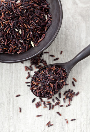 Riceberry rice in a small pile on wooden table, Long grain rice, brown riceの写真素材