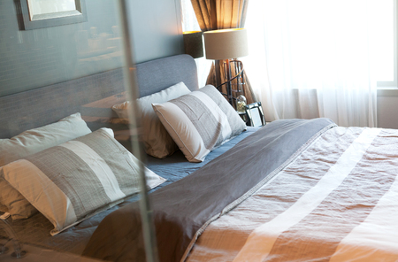 Bedroom interior design with pillows on bed and decorative table lamp, selective focusの写真素材