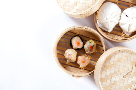 Dim sum and steamed buns in bamboo steamer on white background, Chinese foodの写真素材