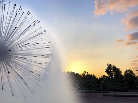 A dandelion fountain spraying mist as the sun setsの写真素材
