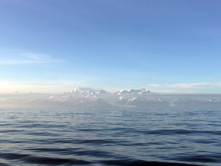 Calm ocean sunset with a large mountain range in the backgroundの写真素材