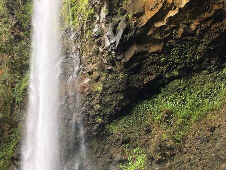 A waterfall cascading down a rocky cliff in Maui Hawaiiの写真素材