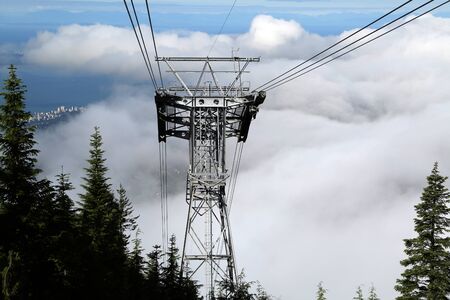 A cable system reaching up through the clouds overlooking the city.の写真素材