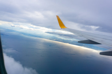 Aerial view of blue sky and cloud seen through window, airplane wing from window