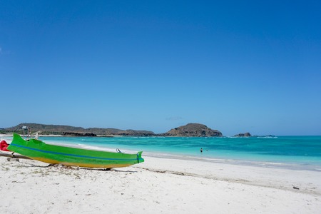 Green boat on the white sands of Pantai Tanjung Aan Beach in Kuta, Lombok, Indonesiaの写真素材