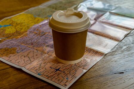 Paper box cup of coffee on a colourful world mapの写真素材
