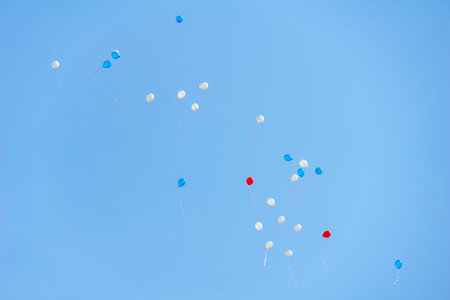 white, blue and red balloons flying in the skyの写真素材