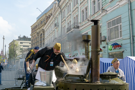 MOSCOW, RUSSIA - MAY 9, 2019: Immortal regiment procession in Victory Day. A man cooking soldier food and distrubuting rationsのeditorial素材