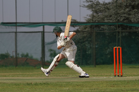 A young school boy playing cricket is tepping out on the front foot attacking the ballの写真素材