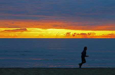 Man jogging on the shore in a sunset lightの写真素材