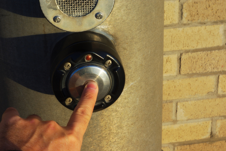 hand with one finger under sunlight pushing pedestrian button to wait for walk signalの写真素材