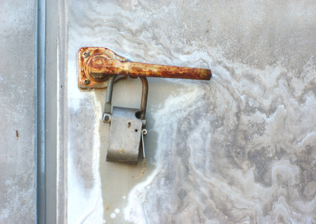rust padlock and old dirty gray steel doorの写真素材