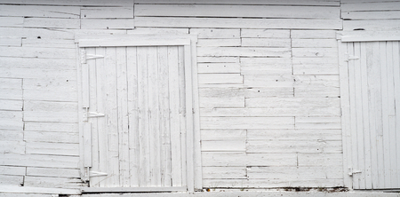 old white peeling paint shed with doors, wood planks background textureの写真素材