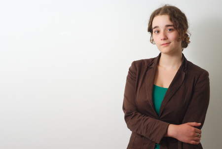 young brunette on white background with brown shirt holding her armの写真素材
