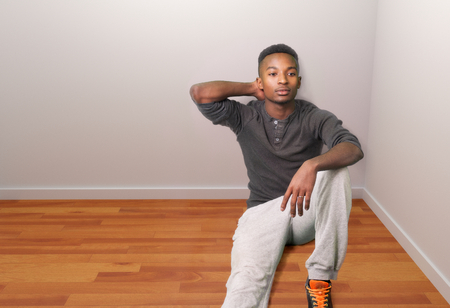 Man sitting on the floor in an empty room wearing sports clothesの写真素材
