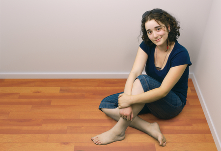 brunette girl with curly hairs sitting on wood floor barefoot top view white walls
の写真素材