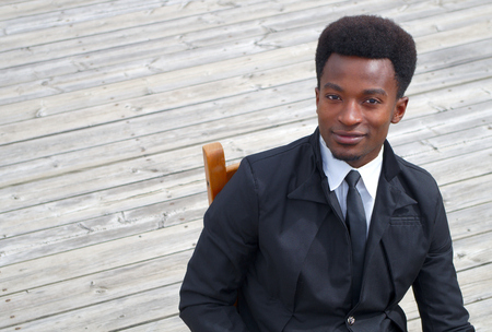 young businessman black suit and tie sitting high angle shot wooden floorの写真素材