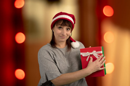 woman with santa hat holding present for christmas lights background red box