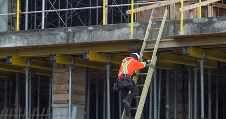 construction worker climbing ladder metal and concrete building structure hard hat