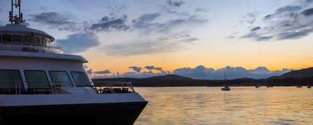 boat and water panoramic landscape orange cloudy sky boats on Memphremagog lake in Magog Quebecの写真素材