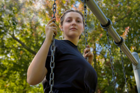girl in a park young woman holding chains standing in a swing at the park active playing lifestyleの写真素材