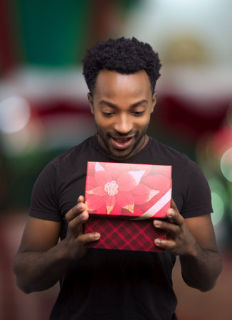 young man receiving a gift and opening box christmas night surprise holiday surprise decorated windowの写真素材