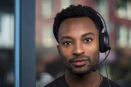 support center contact us helpline customer service assistant african man wearing headset microphone bokeh backgroundの写真素材