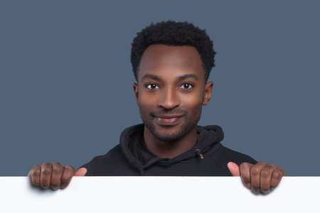 young man holding white page showing blank signboard and smiling copy space board businessman advertisingの写真素材