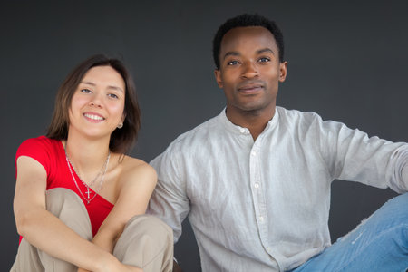 young couple boyfriend and girlfriend smiling together sitting in studioの写真素材