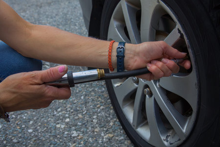 Close-up of hands inflating a car tire with a garage air compressor hose, showcasing essential...