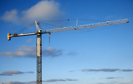 Large industrial tower crane used for heavy lifting on a construction site with a clear blue sky background.の写真素材