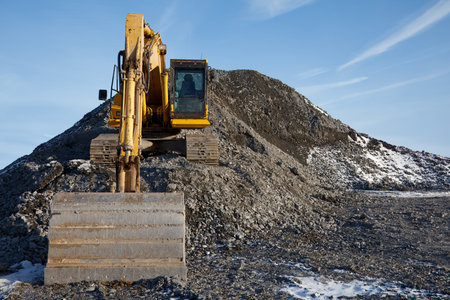 Heavy-duty excavator shovel on a gravel mound at a construction site, front view of industrial work,...