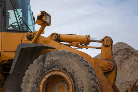 A close-up of heavy construction site equipment with large wheel, shovel, and cabin detail.Perfect for industrial or engineering visuals.の写真素材