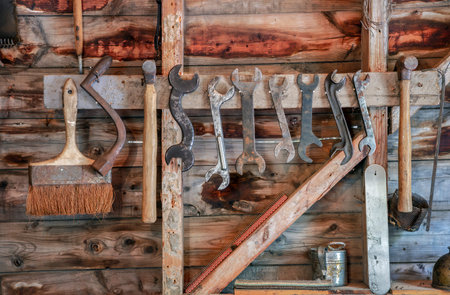 Vintage and rustic carpenter tools including hammers, wrenches, chisels, and paintbrush hanging...