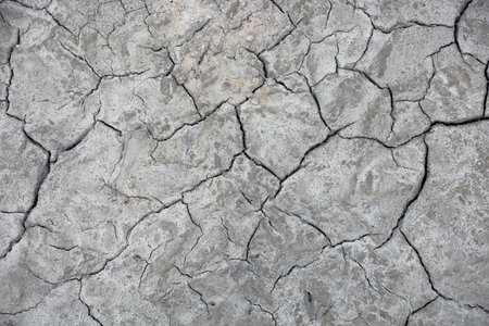 Dry cracked earth surface with deep fissures creates natural abstract texture background. Drought...