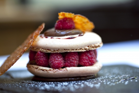 Macaroon, raspberries and biscuit on a plateの写真素材