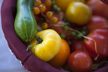 Tomatoes and zucchini in a basketの写真素材