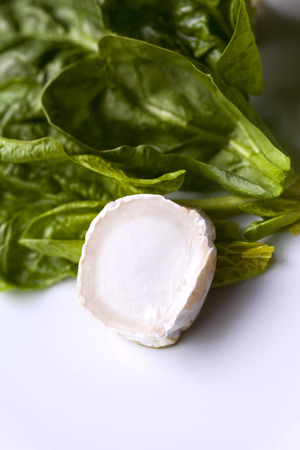 Close up of goat cheese and spinach leaves on a tableの写真素材