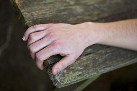 Human hand on the edge of a wooden tableの写真素材