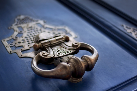 Detail of a bronze knocker on a wooden door Detail of a bronze knocker on a wooden door