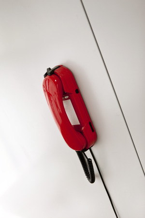 Red phone on a white wall inside a houseの写真素材