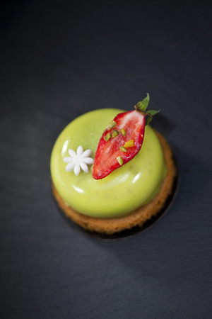 Pistachio mousse and strawberry on a biscuitの写真素材